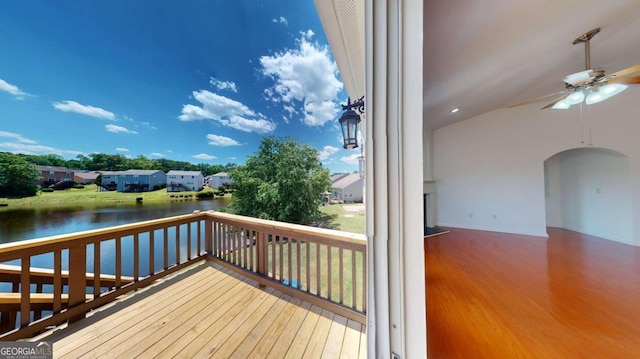 wooden terrace with a water view and ceiling fan