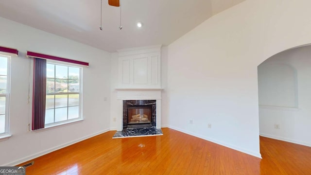 unfurnished living room featuring hardwood / wood-style flooring, ceiling fan, a fireplace, and vaulted ceiling