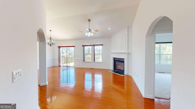 unfurnished living room featuring ceiling fan with notable chandelier, light hardwood / wood-style flooring, and a premium fireplace