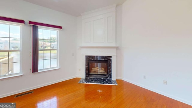 unfurnished living room featuring a high end fireplace and hardwood / wood-style flooring