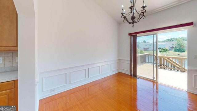 unfurnished room featuring a notable chandelier, light hardwood / wood-style floors, and vaulted ceiling