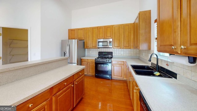 kitchen with tasteful backsplash, sink, stainless steel appliances, and hardwood / wood-style flooring