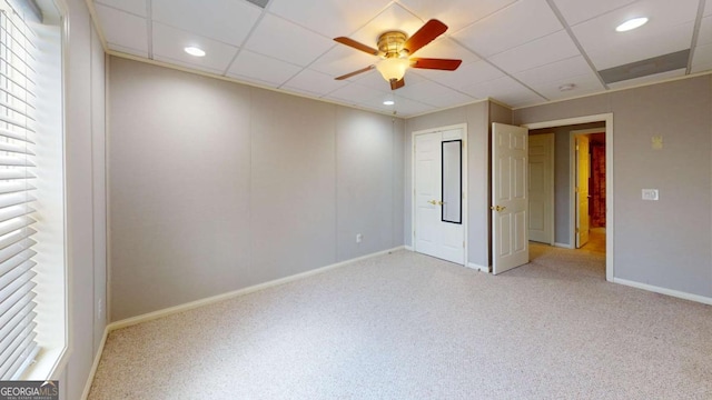 carpeted spare room featuring a paneled ceiling and ceiling fan