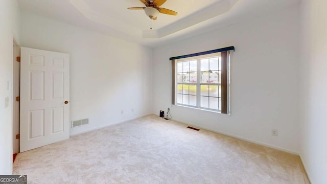 carpeted empty room featuring a tray ceiling and ceiling fan