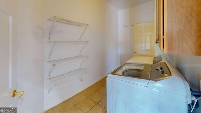 washroom with washer and clothes dryer, cabinets, and light tile patterned floors