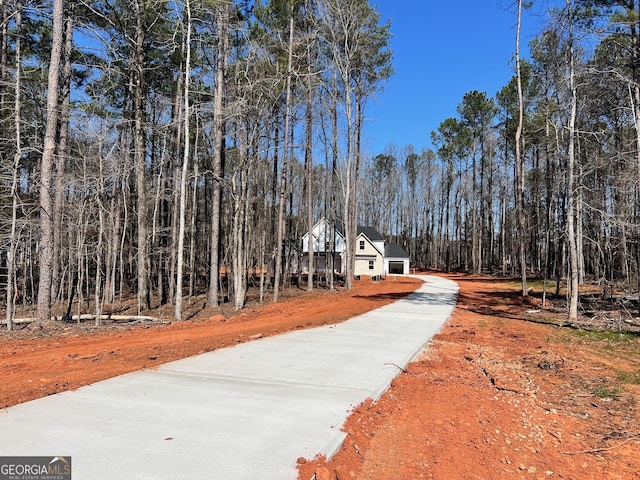 view of street with driveway and a forest view