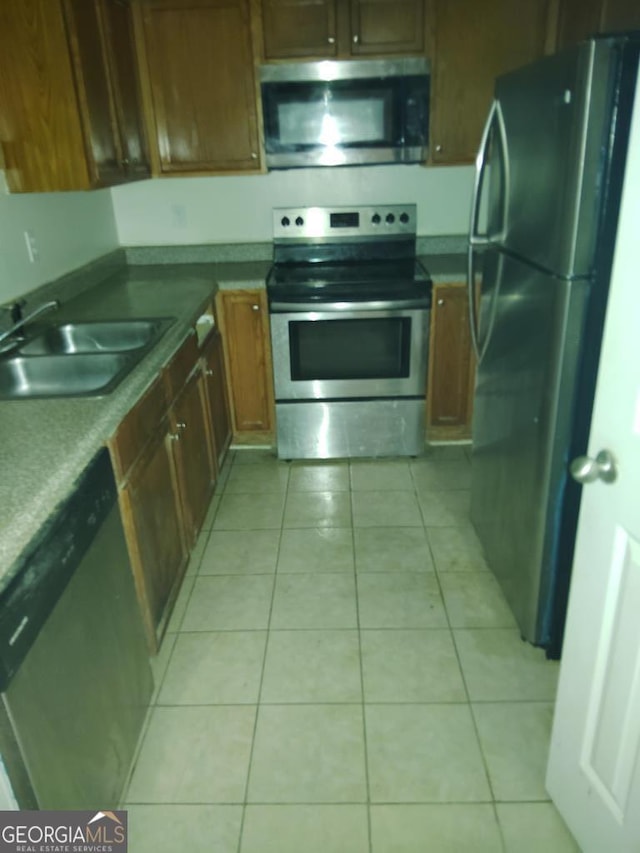 kitchen with sink, light tile patterned floors, and stainless steel appliances