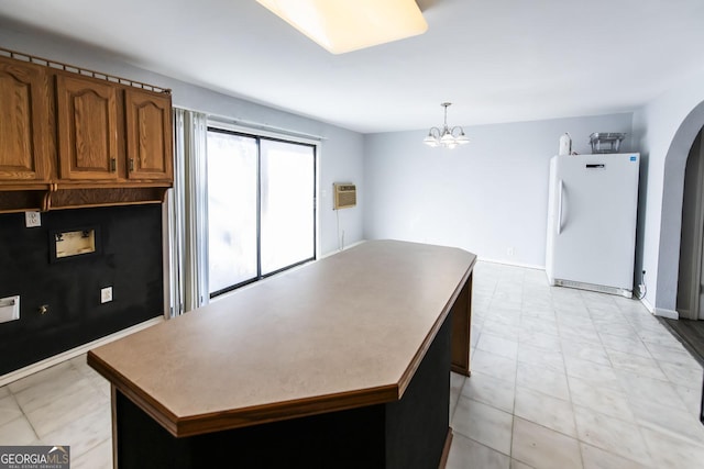 kitchen with a notable chandelier, a kitchen island, a wall unit AC, pendant lighting, and white refrigerator