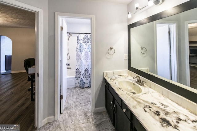 bathroom with wood-type flooring, vanity, a textured ceiling, and shower / tub combo with curtain