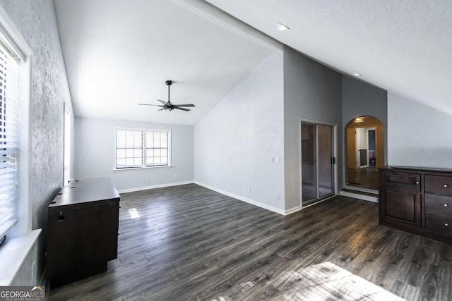 unfurnished living room with ceiling fan, dark hardwood / wood-style floors, and high vaulted ceiling