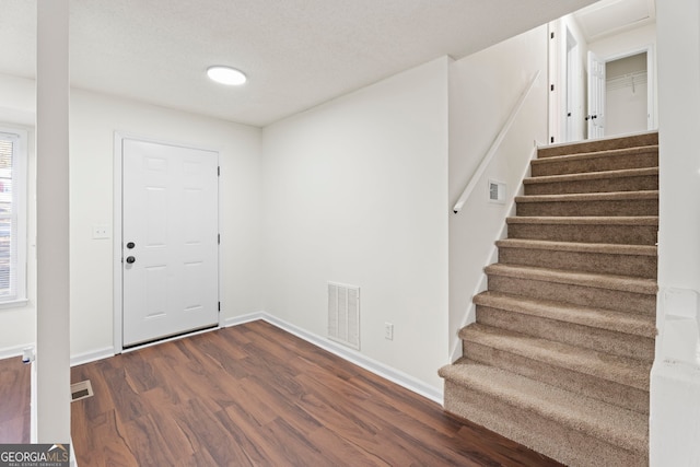 entrance foyer featuring a textured ceiling and dark wood-type flooring