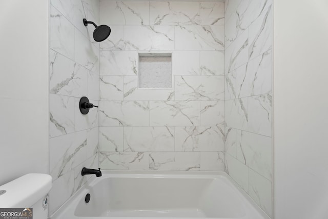 bathroom with tiled shower / bath combo and toilet