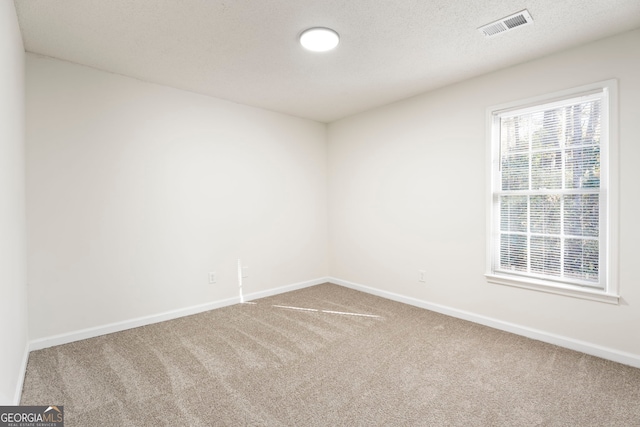 carpeted spare room with a textured ceiling