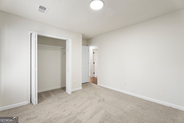 unfurnished bedroom featuring a closet and light colored carpet