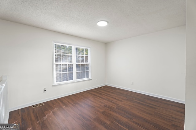 empty room with dark wood-type flooring and a textured ceiling