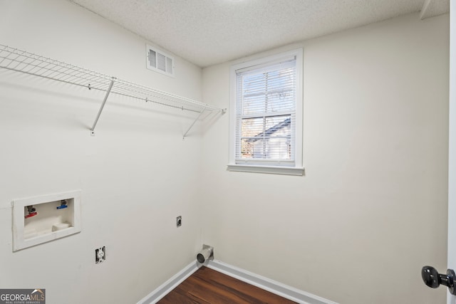 laundry room featuring a textured ceiling, electric dryer hookup, dark wood-type flooring, and hookup for a washing machine