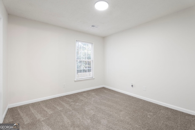 carpeted empty room with a textured ceiling