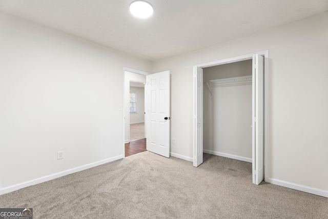 unfurnished bedroom with light carpet and a closet