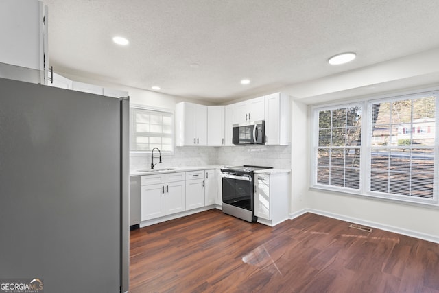 kitchen with white cabinetry, sink, dark hardwood / wood-style flooring, a textured ceiling, and appliances with stainless steel finishes