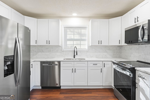 kitchen with white cabinets, appliances with stainless steel finishes, dark hardwood / wood-style flooring, and sink