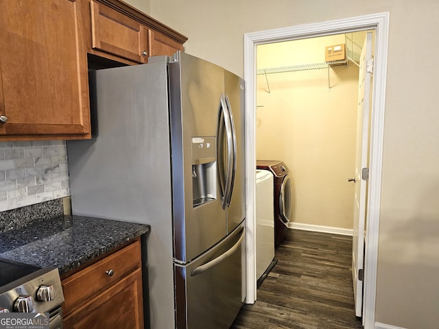 kitchen with decorative backsplash, appliances with stainless steel finishes, dark stone countertops, independent washer and dryer, and dark hardwood / wood-style floors