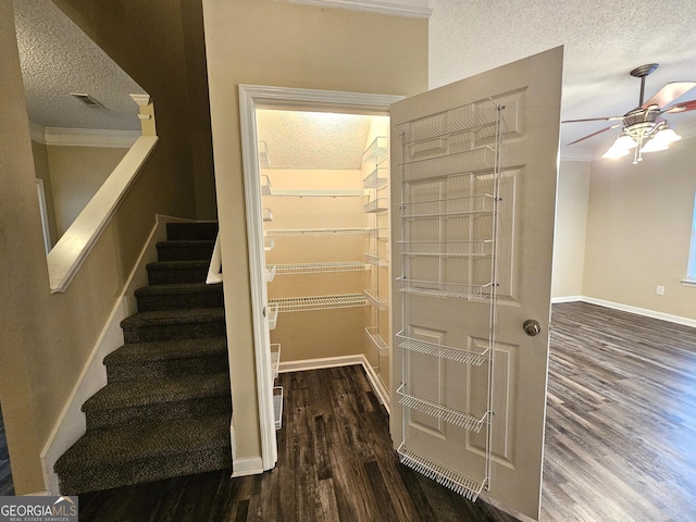 stairway featuring hardwood / wood-style floors, a textured ceiling, ceiling fan, and ornamental molding