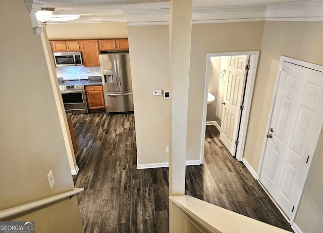 hall with dark hardwood / wood-style flooring, a textured ceiling, and ornamental molding