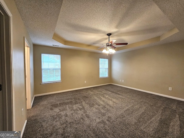 spare room with dark carpet, a raised ceiling, and ceiling fan