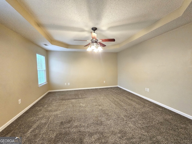 carpeted spare room with a tray ceiling, ceiling fan, and a textured ceiling