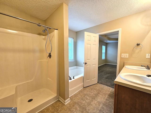 bathroom with a wealth of natural light, vanity, independent shower and bath, and a textured ceiling