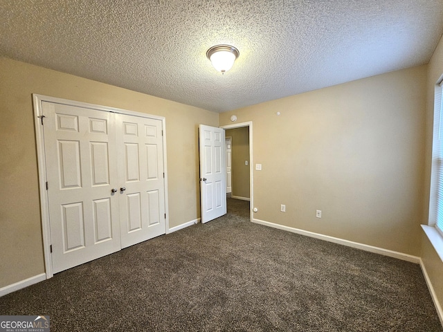 unfurnished bedroom featuring dark colored carpet, a textured ceiling, and a closet