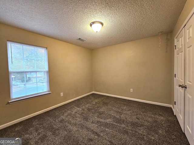 carpeted empty room featuring a textured ceiling