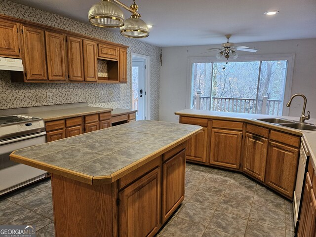 kitchen with a center island, sink, ceiling fan, decorative light fixtures, and white range oven