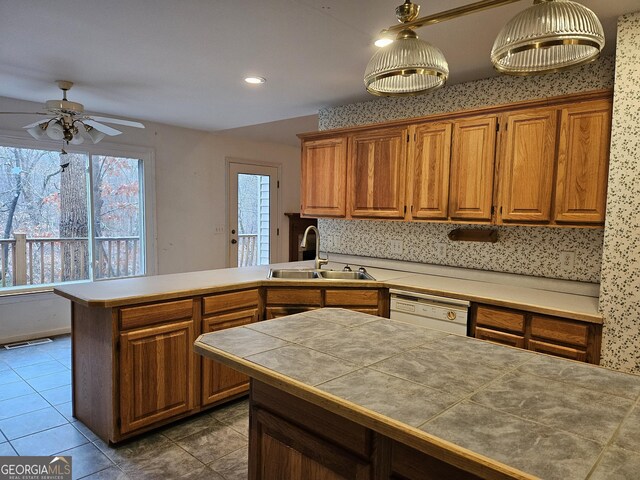 kitchen with ceiling fan, sink, decorative light fixtures, dishwasher, and tile counters