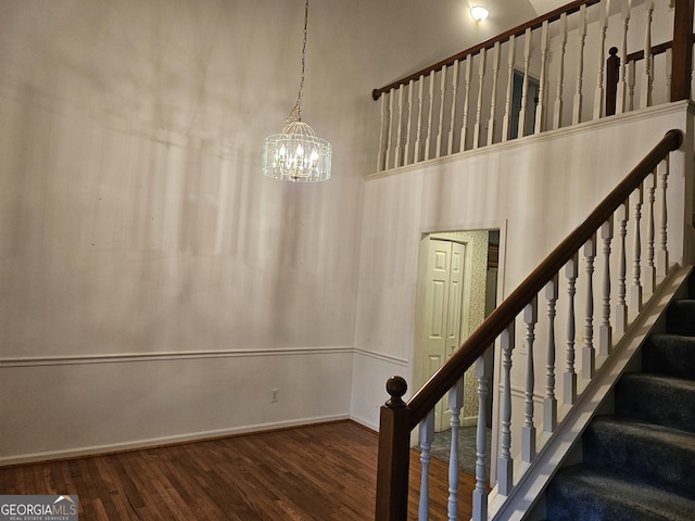 stairway featuring a chandelier, wood-type flooring, and a high ceiling