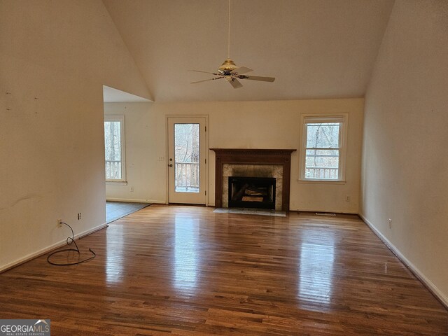 unfurnished living room with wood-type flooring, high vaulted ceiling, ceiling fan, and a premium fireplace