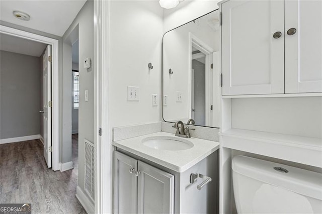 bathroom with toilet, vanity, and hardwood / wood-style flooring