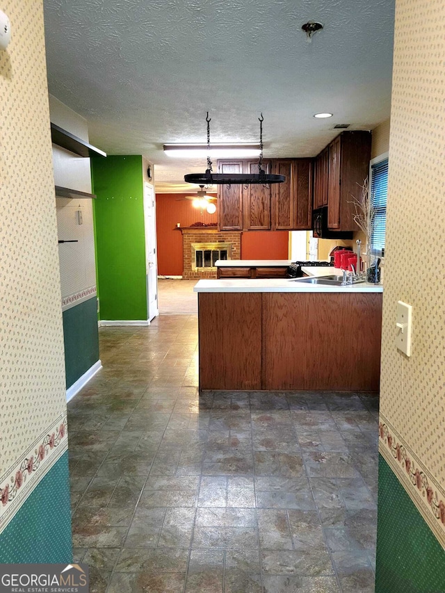 kitchen with kitchen peninsula, a textured ceiling, and a fireplace