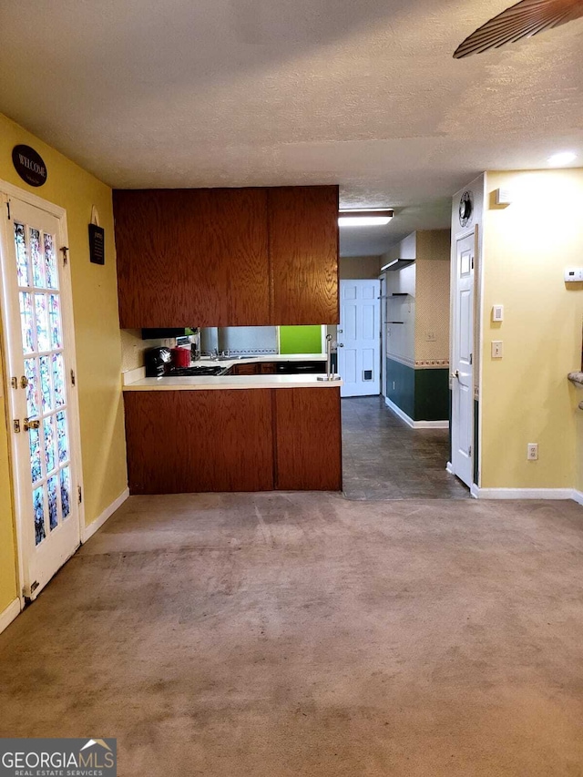 kitchen with kitchen peninsula, a textured ceiling, and dark colored carpet