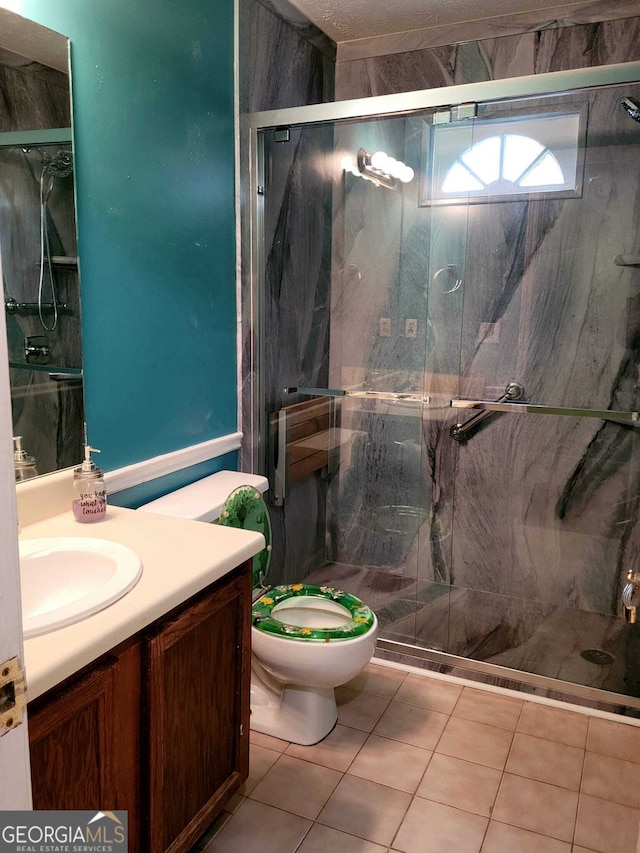 bathroom with tile patterned floors, vanity, an enclosed shower, and toilet