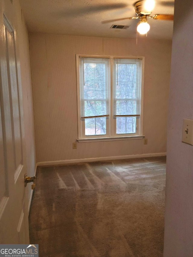 carpeted spare room featuring a textured ceiling and ceiling fan