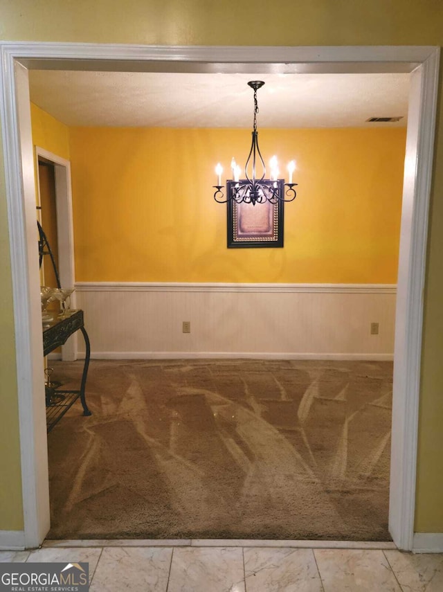 unfurnished dining area featuring a notable chandelier and carpet floors