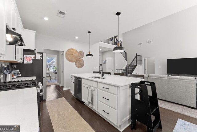 kitchen featuring white cabinets, decorative light fixtures, stainless steel appliances, an island with sink, and sink