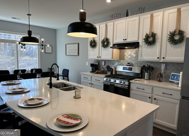 kitchen featuring an island with sink, white cabinets, decorative light fixtures, backsplash, and stainless steel appliances