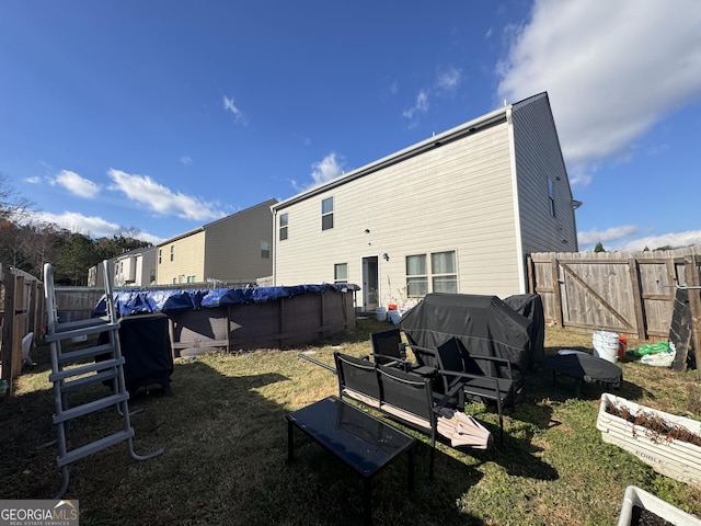 rear view of house with a covered pool and a lawn