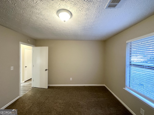 spare room featuring carpet floors and a textured ceiling