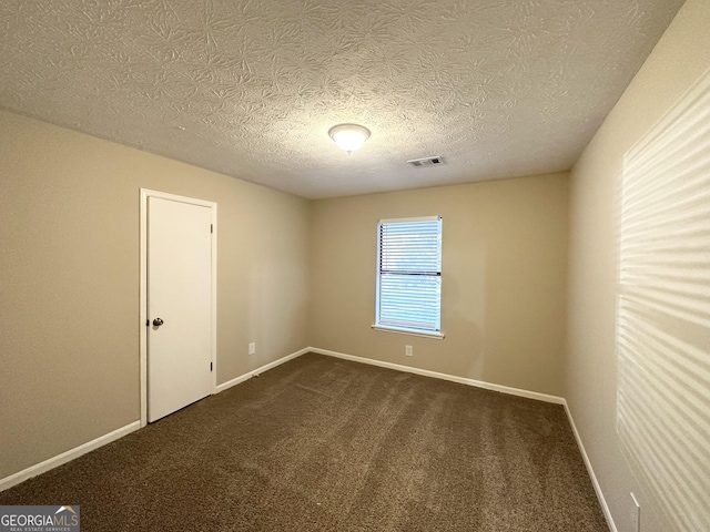 empty room featuring a textured ceiling and dark colored carpet