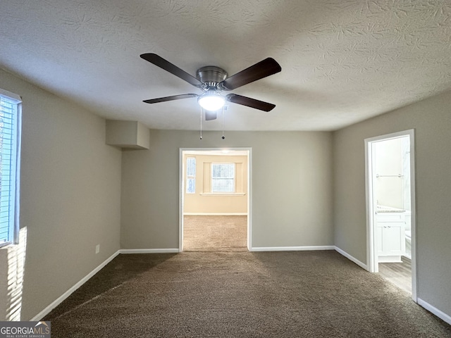 carpeted empty room with a textured ceiling, plenty of natural light, and ceiling fan