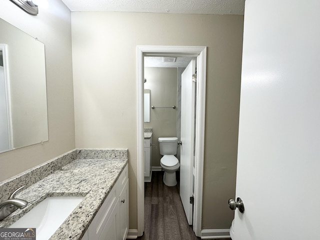 bathroom with vanity, wood-type flooring, a textured ceiling, and toilet