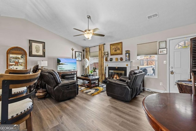 living room featuring hardwood / wood-style flooring, ceiling fan, a textured ceiling, and vaulted ceiling